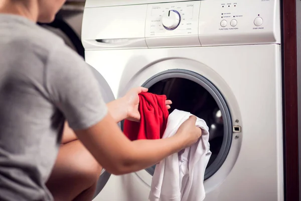 Loading white and color clothes in washing machine. Washing clothes in different colors