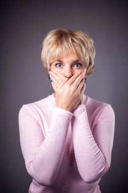 Kısa sarı saçlı bir kadın elleriyle ağzını kapattı. İnsanlar ve duygular