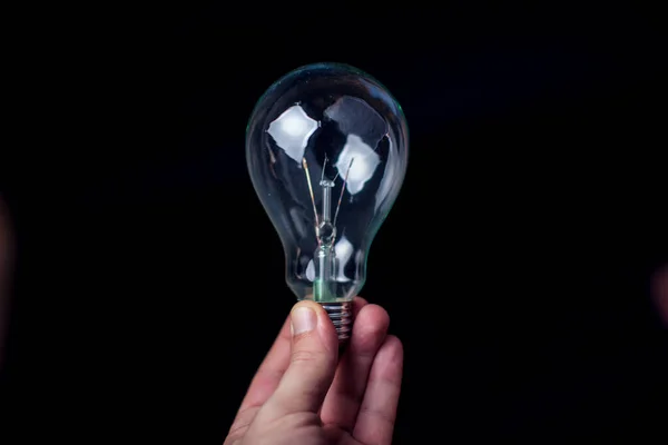 Light bulb in hand in front of black background. Energy or idea concept