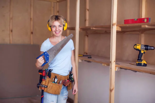 Handy woman with short hair with headphones works with saw, try to licks it.