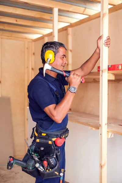 Handyman with yellow headphones works with hammer does repair.