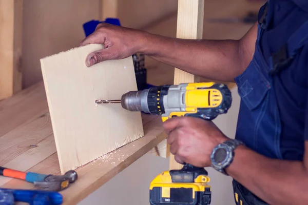 Handyman with yellow headphones works with drill does repair.