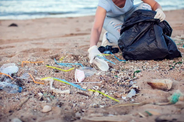 身穿蓝色衬衫 头戴白色手套 头戴黑色大包的女人在海滩捡垃圾 环境保护和地球污染概念 — 图库照片