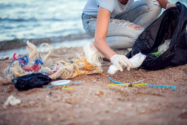 白い手袋と大きな黒いパッケージで青いシャツの女性は ビーチでゴミを収集します 環境保護と地球汚染の概念 — ストック写真