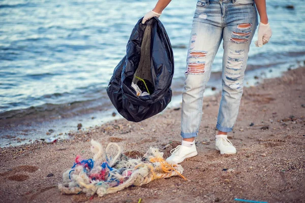 身穿蓝色衬衫 头戴白色手套 头戴黑色大包的女人在海滩捡垃圾 环境保护和地球污染概念 — 图库照片