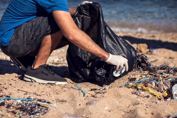 带着黑包的志愿者在海滩上捡垃圾 环境污染概念 — 图库照片