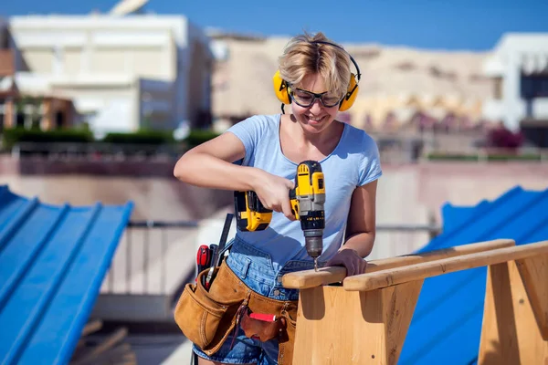 Handy woman with toolsbelt and yellow drill in her hands outdoors