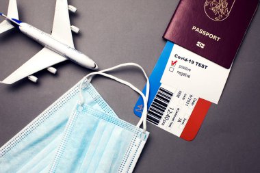 COVID-19 salgını sırasında seyahat, uçak biletli pasaport, covid-19 pozitif test, tıbbi maskeler ve gri arka planda uçak, havaalanı güvenliği ve güvenlik kontrolü konsepti