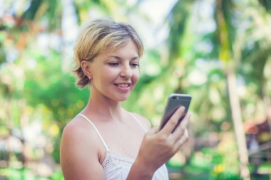 Açık havada cep telefonu kullanan güzel bir kadının portresi.