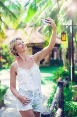 Gülümseyen genç kadın, dışarıda bir selfie çek.