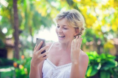 Açık havada cep telefonu kullanan güzel bir kadının portresi.