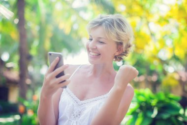 Açık havada cep telefonu kullanan güzel bir kadının portresi.