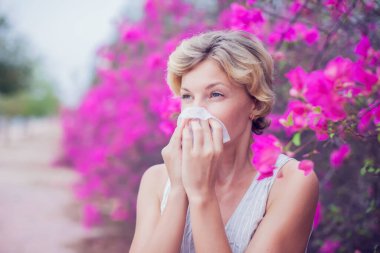 Alerji belirtileri olan bir kadın burnunu siliyor.