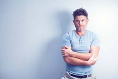 Gri arka planda yakışıklı bir adam kameraya bakıyor..