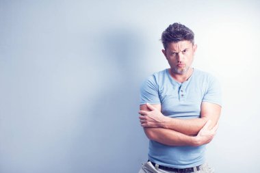 Gri arka planda yakışıklı bir adam kameraya bakıyor..