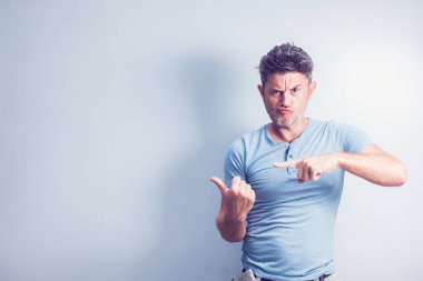 Orta yaşlı bir adam, mavi arka planda izole edilmiş, kameraya olumlu bir hareket, hoşlanma ve onaylama ifadesi göstererek gülümsüyor.