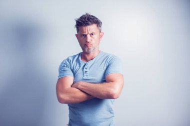 Gri arka planda yakışıklı bir adam kameraya bakıyor..