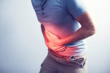 İnsanlar, sağlık ve sorun konsepti - gri arka plan yüzünden karnı ağrıyan mutsuz bir adam