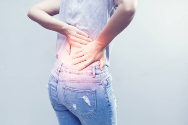 Sırtına acı dolu bir ifadeyle dokunan genç bir kadının portresi uzun çalışma saatlerinden sonra sırt ağrısı çeken sağlıklı bir konsept..