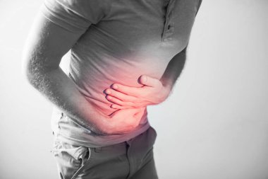 İnsanlar, sağlık ve sorun konsepti - gri arka plan yüzünden karnı ağrıyan mutsuz bir adam