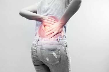 Sırtına acı dolu bir ifadeyle dokunan genç bir kadının portresi uzun çalışma saatlerinden sonra sırt ağrısı çeken sağlıklı bir konsept..