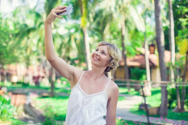 Gülümseyen genç kadın, dışarıda bir selfie çek.