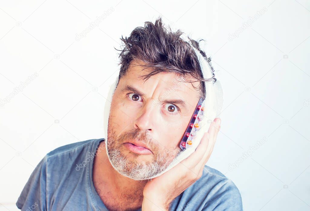 Man in medical bandage and pills isolated on gray background
