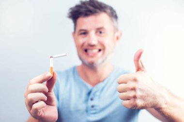 Elinde kırık bir sigarayla gülümseyen genç adam.