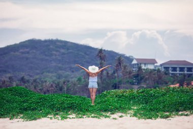 Mutlu kadın, dağda günbatımının arka planında ellerini kaldırarak ayakta duruyor.