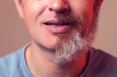 Kahverengi arka planda yarım sakallı ve saçlı bir adam portresi.