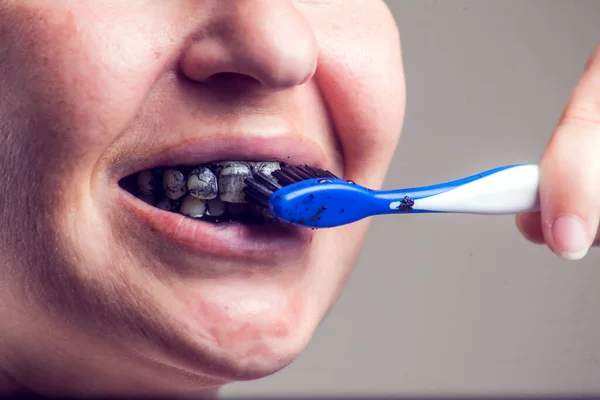 Woman cleans her teeth with charcoal toothpaste. People and healthcare concept.