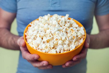 Patlamış mısır kutusu tutan eller. İnsanlar ve yemek konsepti