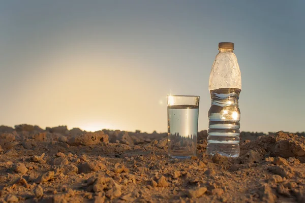 沙漠中沙滩上的玻璃杯和一瓶水 炎热和干旱的概念 — 图库照片