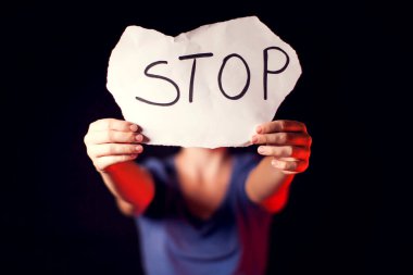 Kadın, siyah arka planda kendisine yardım etmesi için elinde mesajla kâğıt tutuyor. İnsanlar, aile içi şiddet, suç kavramı