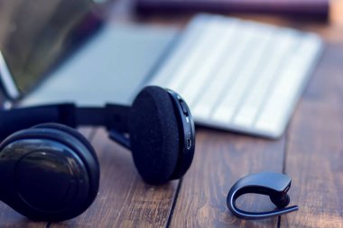 Kulaklıklar ve dizüstü bilgisayarlar dışarıdaki ahşap masada. Teknoloji ve yaşam tarzı kavramı