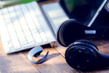 Kulaklıklar ve dizüstü bilgisayarlar dışarıdaki ahşap masada. Teknoloji ve yaşam tarzı kavramı