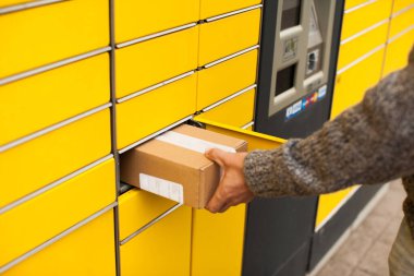 Sarı self-servis terminal makinesi. Adam bir paket alır