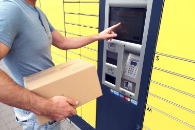 Paketi depolamak için otomatik self servis terminali ya da dolap kullanan bir adam