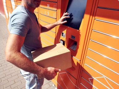 Paketi depolamak için otomatik self servis terminali ya da dolap kullanan bir adam
