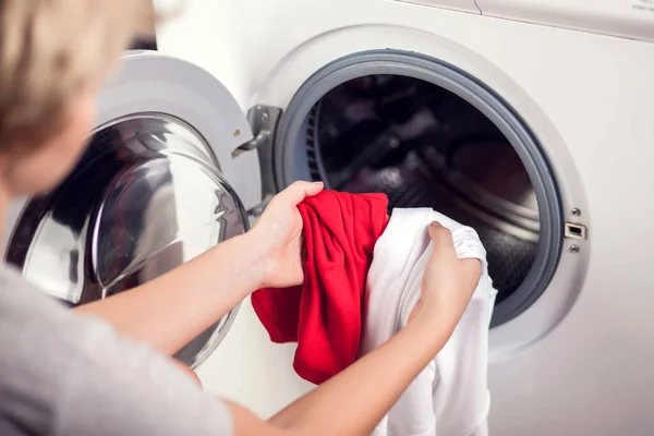 Loading white and color clothes in washing machine. Washing clothes in different colors