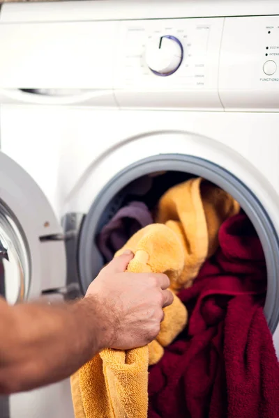 Loading clothes in washing machine. Housework, laundry concept