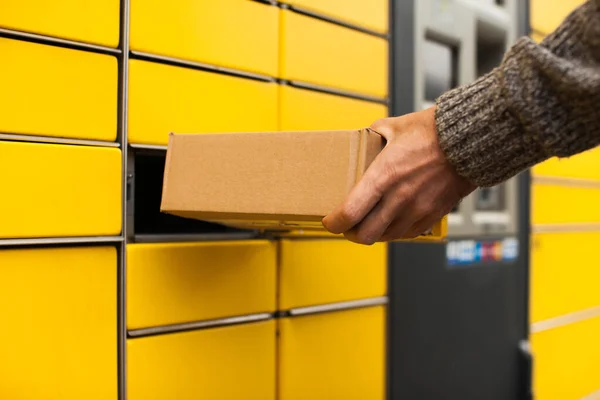 Sarı self-servis terminal makinesi. Adam bir paket alır