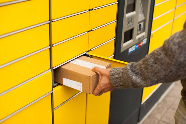 Yellow self-service post terminal machine. Man recieve a parcel