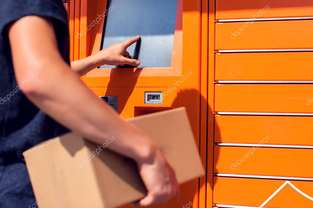 Man using automated self service post terminal machine or locker to deposit the parcel for storage
