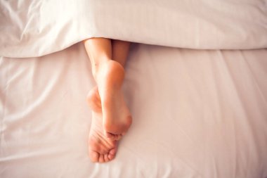 Kadın bacakları yatağın üstünde. Yakın plan çekim. İnsanlar, güzellik, sağlık ve yaşam tarzı kavramı