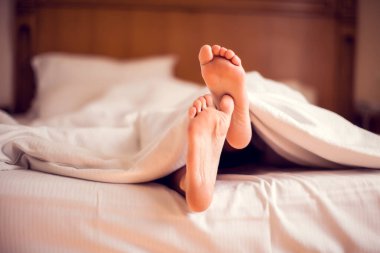 Battaniyenin altındaki bir yatakta kadının ayaklarını kapat. İnsanlar ve yaşam tarzı kavramı