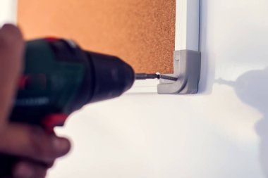 Elektrikli tornavidayla çalışan bir müteahhit. Duvardaki tahtayı tamir et.