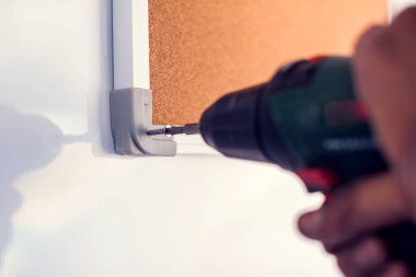 Elektrikli tornavidayla çalışan bir müteahhit. Duvardaki tahtayı tamir et.