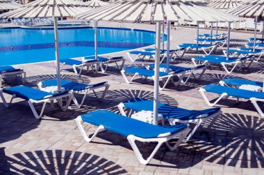 Plaj sandalyeleri yüzme havuzunun yanında. Tatil ve yaz konsepti