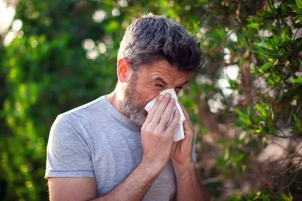 男は木の開花の前で鼻を吹く 春のアレルギーと医療の概念 — ストック写真